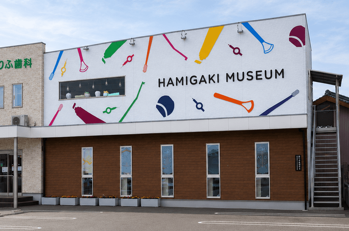 歯みがきミュージアムの外観。カラフルな歯みがき用品のイラストが描かれた壁面の建物。
