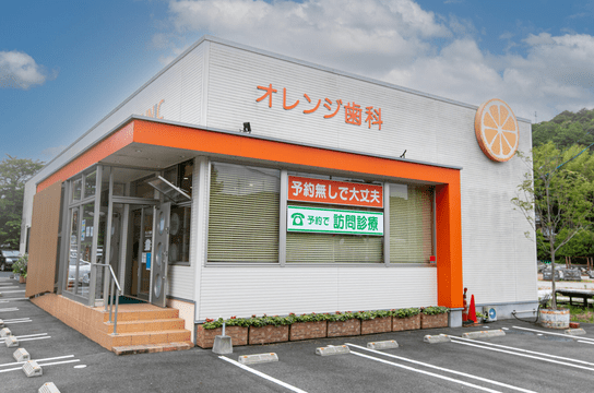 オレンジ歯科医院の外観。白い壁にオレンジ色の縁取りが目を引く、現代的なデザインの建物。