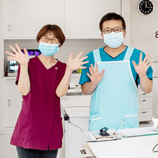 手を振って笑顔を見せる2人のスタッフ。