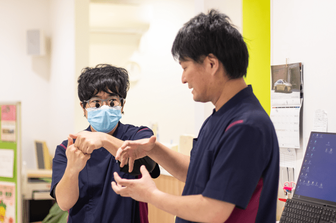 指導医が若手の歯科医師に付き添いながら診療を行う様子